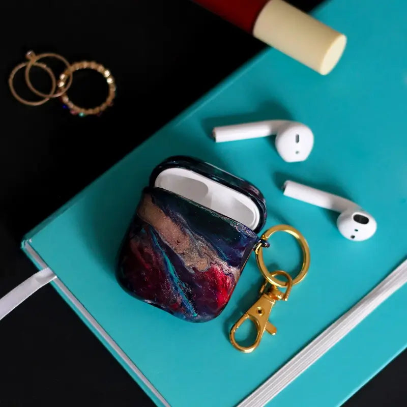 Funda para proteger AirPods, pintada a mano por Ana Tere Canales. Un diseño en colores azules, verde y dorado. Inspirado en nuestro mundo interior, conectar con nuestra esencia, escuchar a nuestro corazón.
