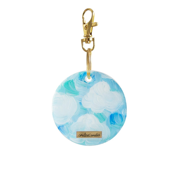 Llavero circular pintado a mano por Ana Tere Canales. Un diseño inspirado en
las nubes en colores blanco, aqua y celeste.
