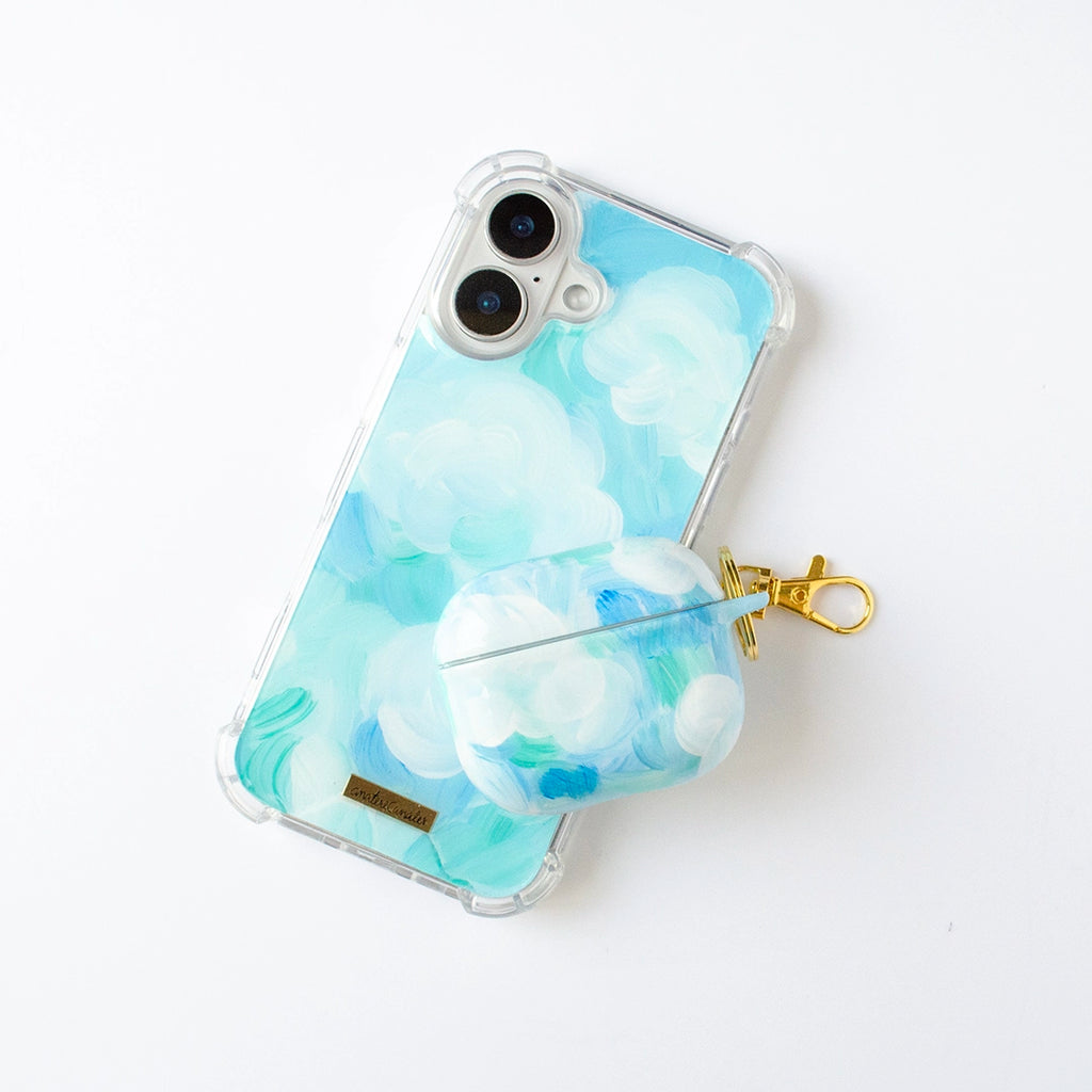 Fundas para proteger iPhone y AirPods, pintadas a mano por Ana Tere Canales. Un diseño con color blanco, aqua y celeste, representando nubes.