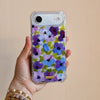 Funda para proteger iPhone, pintada a mano por Ana Tere Canales. Un diseño de flores en morados y verdes.