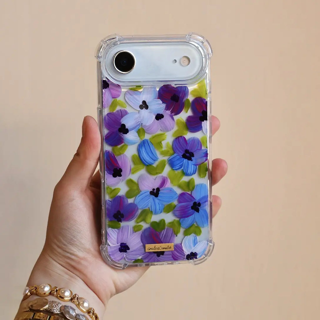 Funda para proteger iPhone, pintada a mano por Ana Tere Canales. Un diseño de flores en morados y verdes.