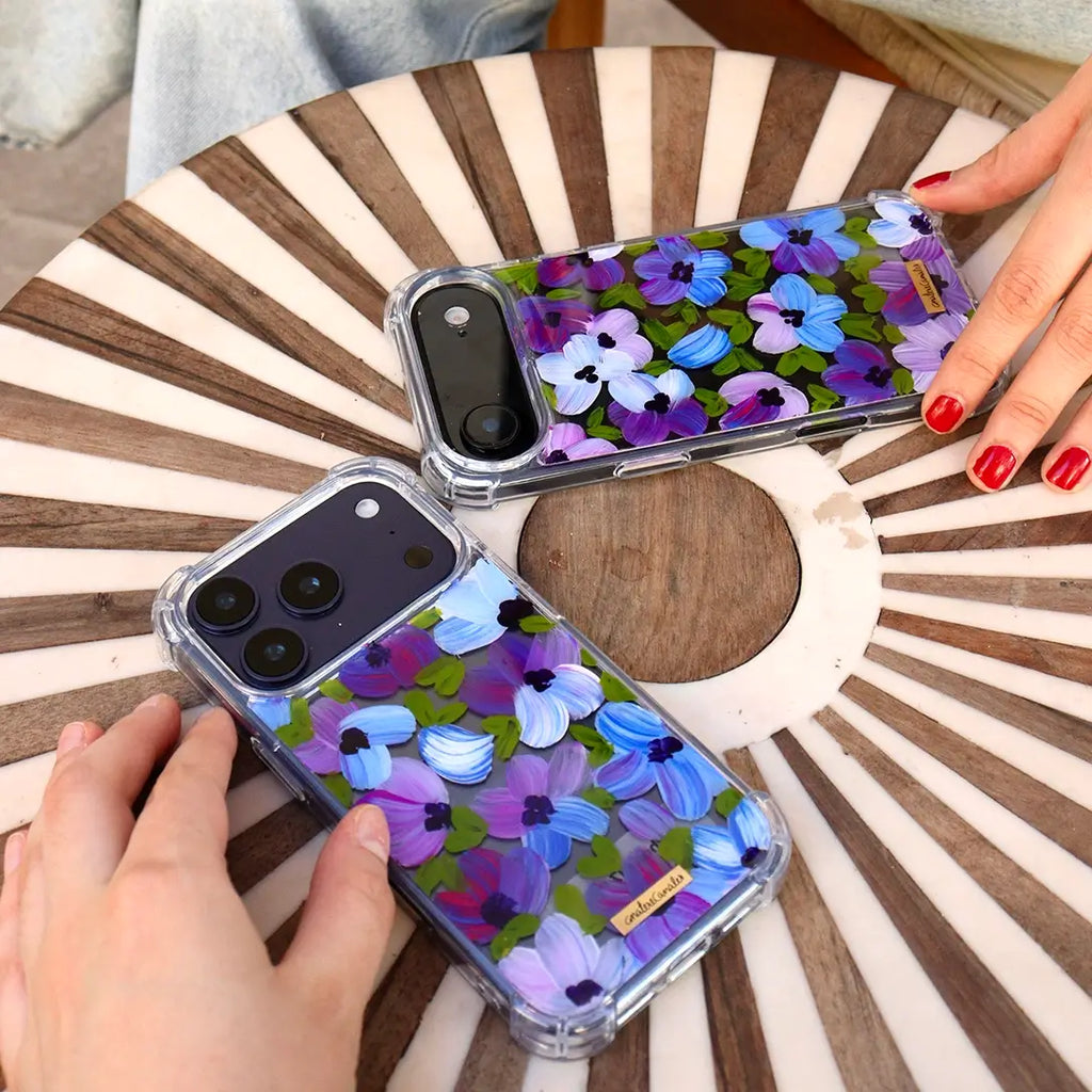 Funda para proteger iPhone, pintada a mano por Ana Tere Canales. Un diseño de flores en morados y verdes.