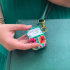 Funda para AirPods Paraíso pintados a mano por Ana Tere Canales. Un diseño artístico inspirado en un paraíso tropical en tonos azul, verde y arena
