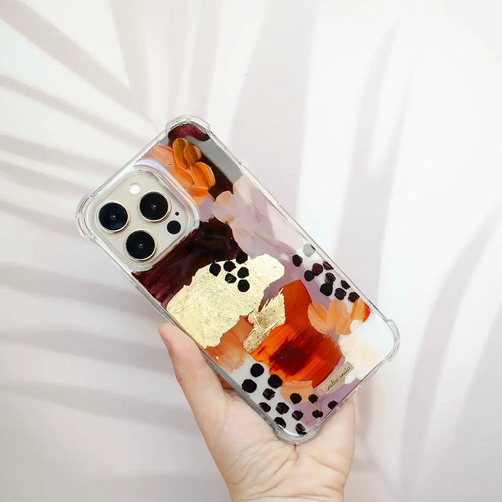 Funda para proteger iPhone, pintada a mano por Ana Tere Canales. Un diseño en tonos tierra con toques dorados.