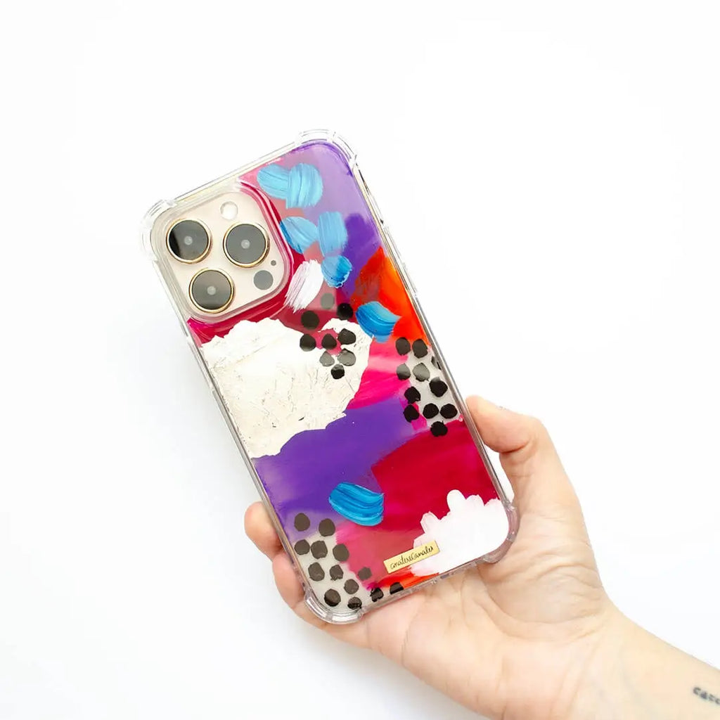 Funda para proteger iPhone, pintada a mano por Ana Tere Canales. Un diseño de colores rojos, morado, rosa, blanco, negro y toques plateados.